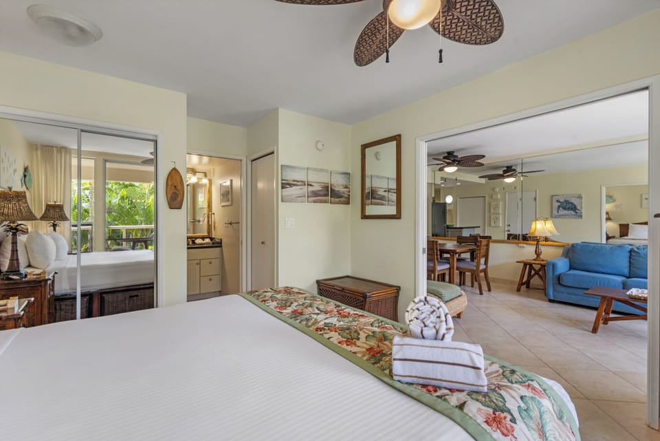 Relax in your tropical-themed bedroom with ceiling fan and beautiful view of the lush outdoor balcony through sliding doors.