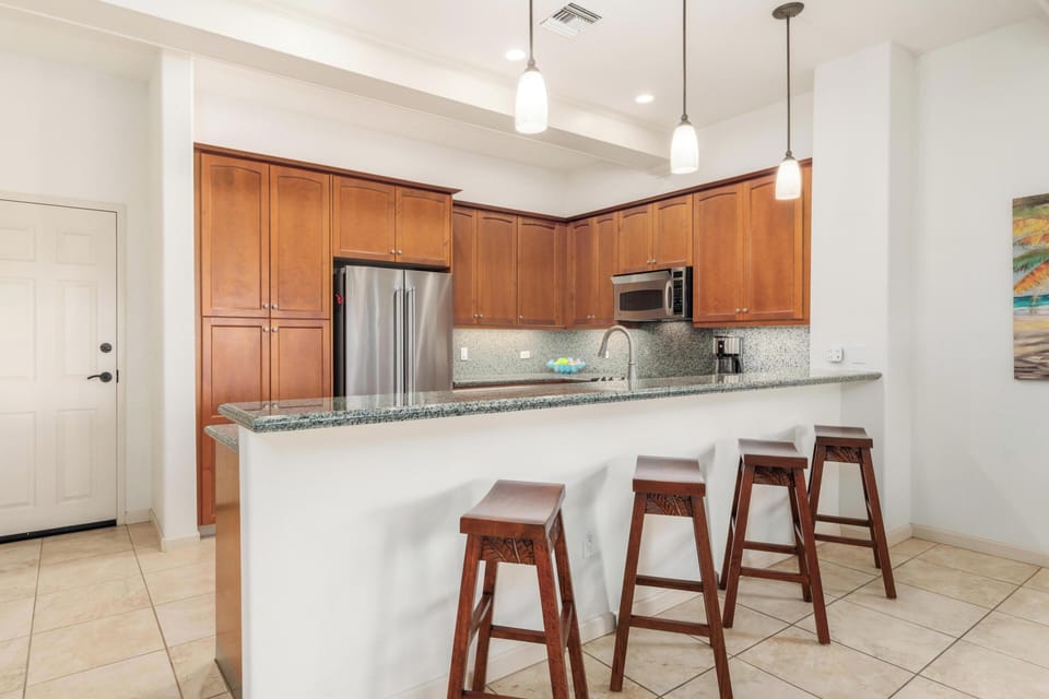 Your fully equipped kitchen awaits with granite counters, stainless appliances, and a breakfast bar where you can enjoy morning coffee.