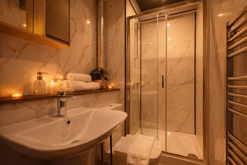 Modern bathroom with walk-in shower, premium toiletries, fresh white towels, and hairdryer provided