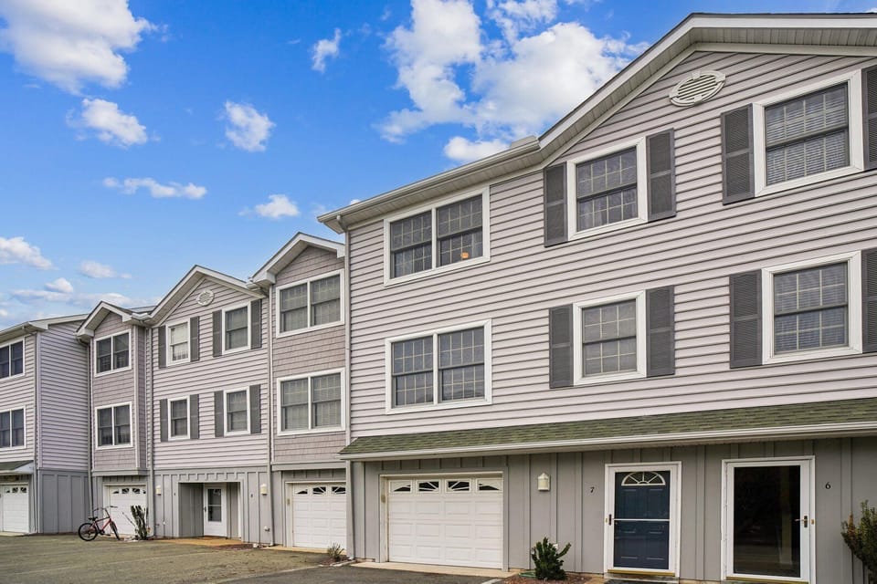 Modern multi-unit property with private garage access and convenient ground-floor entry under bright coastal skies.