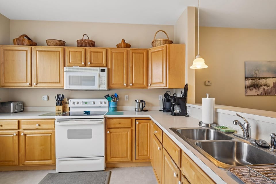 Your spacious kitchen offers everything you need to prepare home-cooked meals, with warm wood cabinetry, ample counter space, and modern appliances including a coffee maker to start your mornings right.
