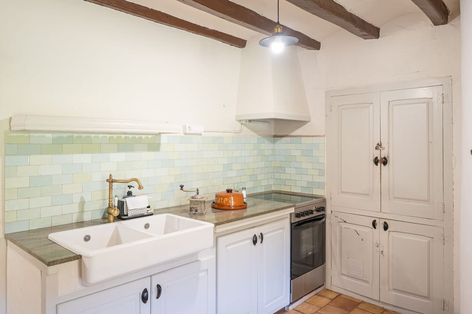 Farmhouse kitchen at Famada casa rural, fully equipped for a family or group of up to 11. In the character-rich interior of this 1850 Catalan casa rural, cooking together is as much part of the holiday as the Garrotxa scenery outside.