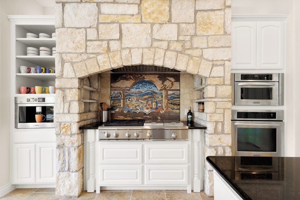Hand-laid mosaic backsplash inside a full stone kitchen arch