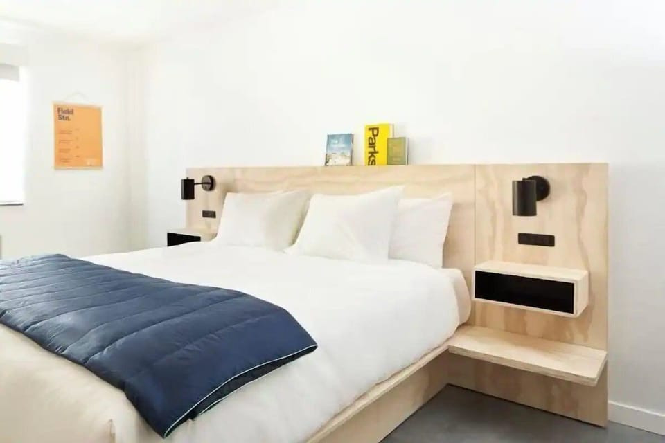 Unwind in crisp linens with sleek, modern bedside lighting.
