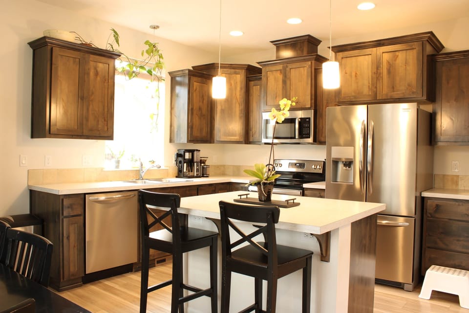 Cook and gather in a fully equipped kitchen featuring stainless steel appliances, custom cabinetry, 