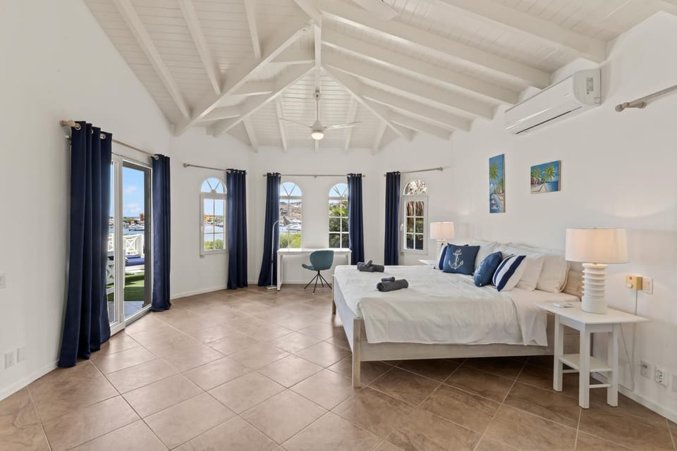 Spacious primary bedroom with high ceilings and direct access to outdoor living spaces