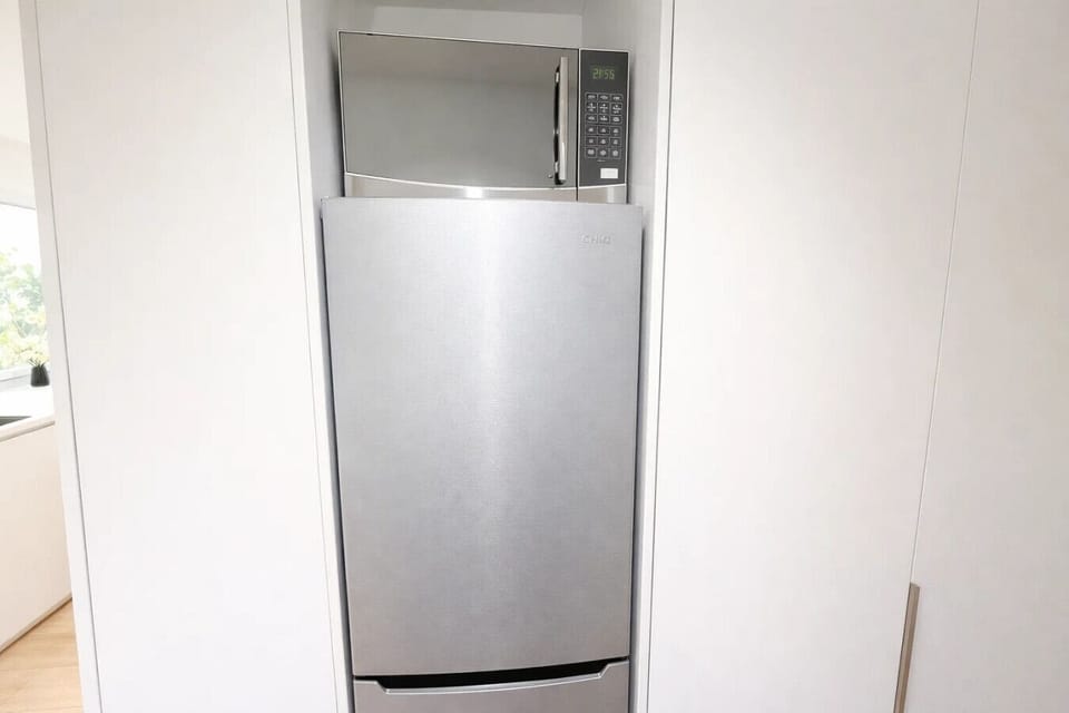 Full-size refrigerator and microwave neatly integrated into the white cabinetry — practical kitchen essentials that make longer stays and self-catering comfortable and convenient.