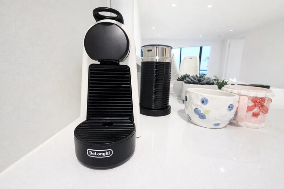 Nespresso machine and milk frother on the kitchen counter, paired with charming ceramic mugs — everything you need to brew a quality coffee from the comfort of your own space.