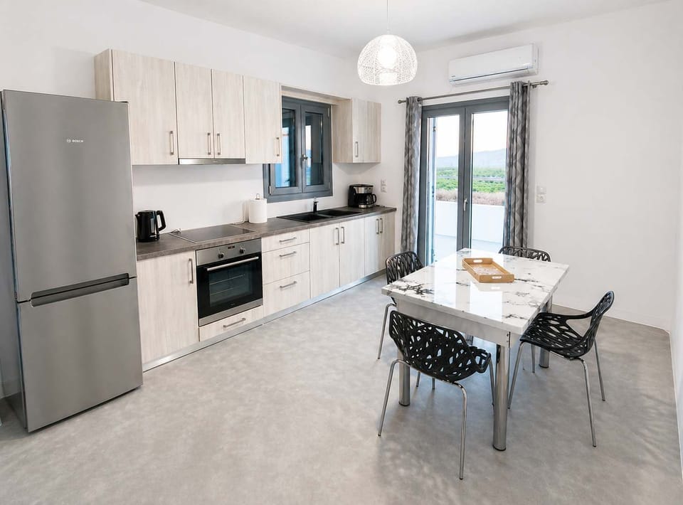 Modern, fully equipped kitchen with bright natural light and a stylish dining area. Perfect for preparing meals and enjoying them with family or friends, with direct access to the outdoors for a seamless indoor-outdoor living experience