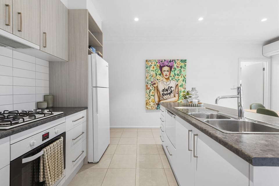 Sleek galley kitchen with island, gas cooktop, and vibrant art