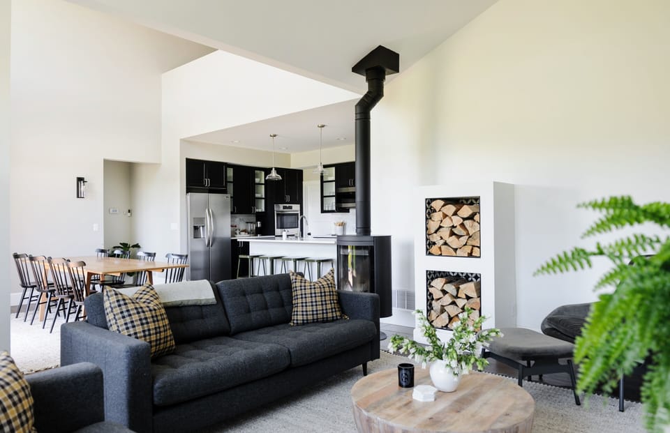 The main living room centers on a wood-burning stove with clear sight lines into the dining area and kitchen beyond.