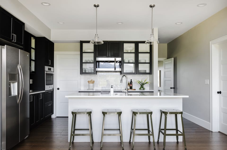 The chef's kitchen features a spacious island, glass-front cabinetry, and bar seating for four under pendant lighting.