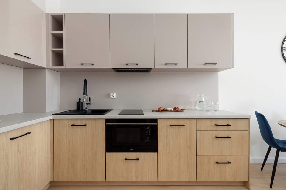 A straight-on view of the kitchenette featuring sleek cabinets and a stovetop. The design is functional and modern, with a neutral color palette and subtle lighting.