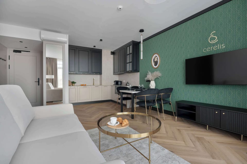 An open-concept living space connects the kitchen and lounge, featuring chevron-patterned wooden flooring and a modern TV unit.