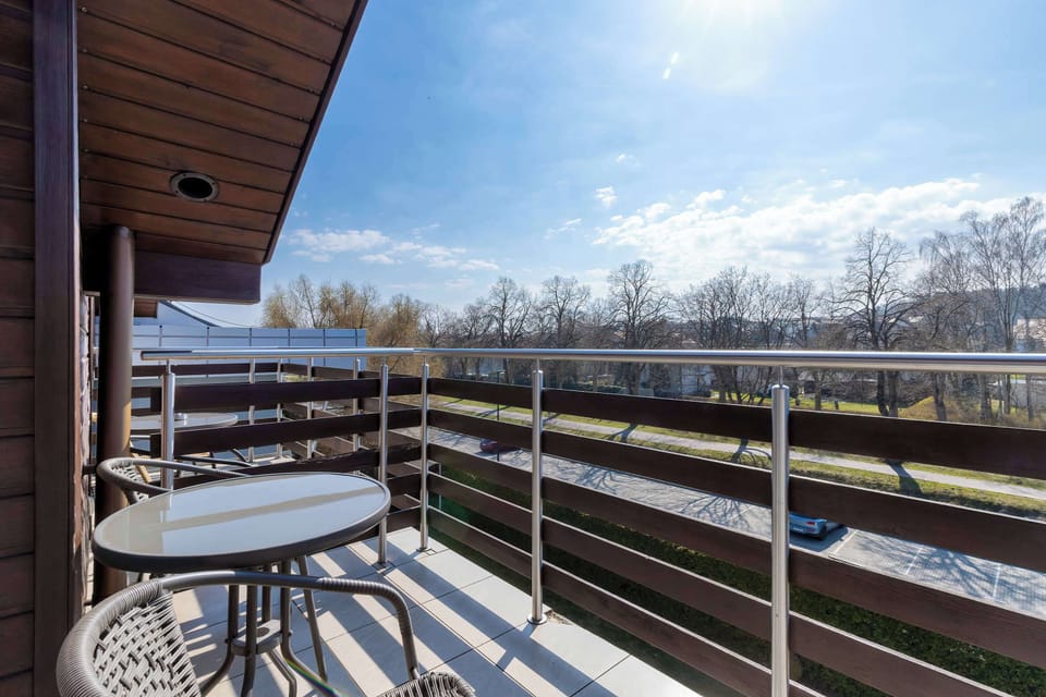 A balcony with a small table and chairs overlooking the outdoors. It’s a nice spot to relax and enjoy fresh air.