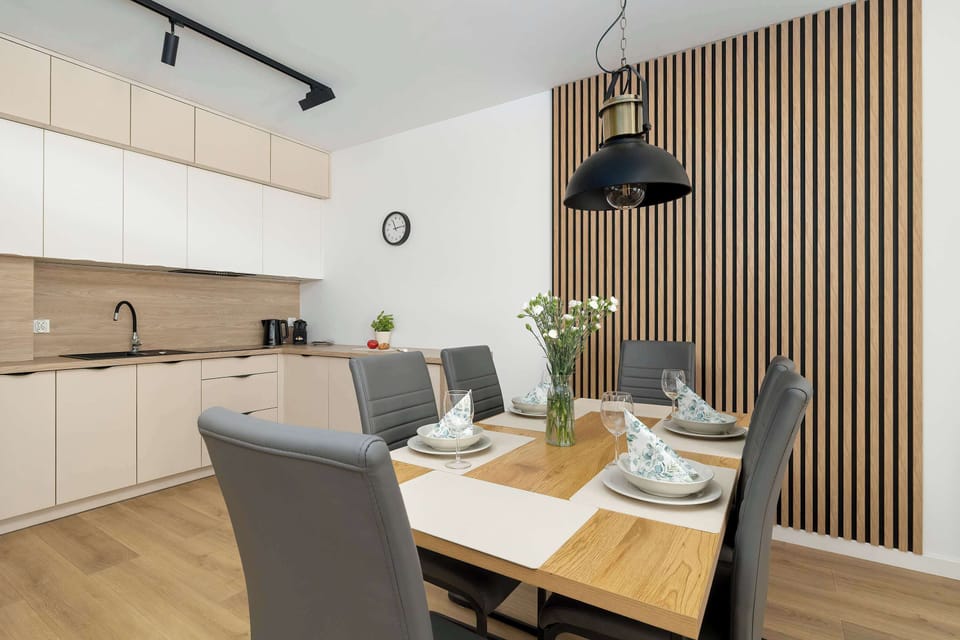 A dining area with a table set for a meal, placed next to a modern kitchenette.