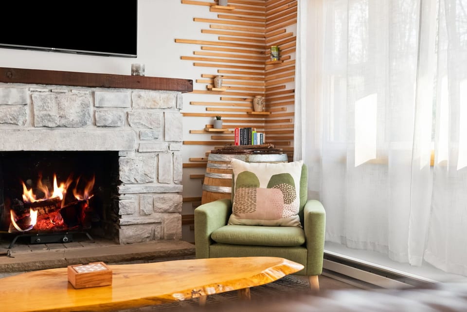 Bright living room with stone fireplace, TV, and reading chair