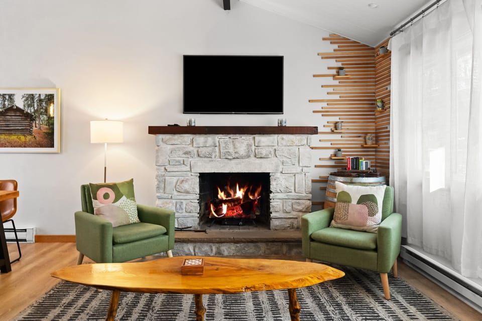 Crackling stone fireplace with green armchairs and mounted TV
