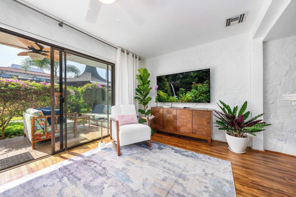 Relax in your stylish living room with tropical garden views, modern TV entertainment, and lush greenery creating a peaceful retreat.