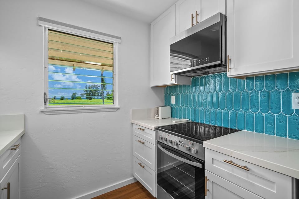 Step into your fully equipped kitchen featuring stunning turquoise tile backsplash and modern appliances,