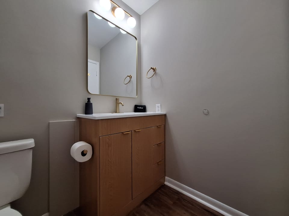 Modern bathroom vanity with stylish brass finishes and warm wood storage