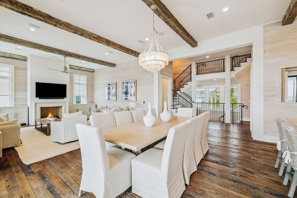 Gather around your elegant dining table beneath soaring beams and a sparkling chandelier, with your cozy fireplace creating the perfect ambiance.