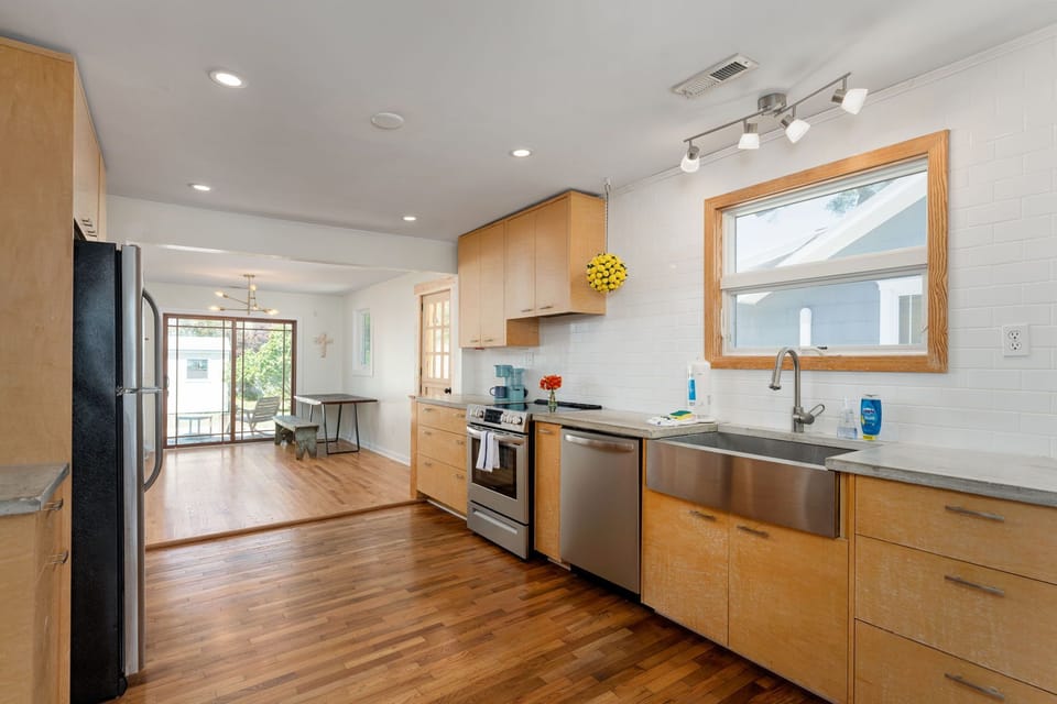 Your modern kitchen flows seamlessly into bright living space, featuring sleek appliances and warm wood finishes for effortless meal prep.