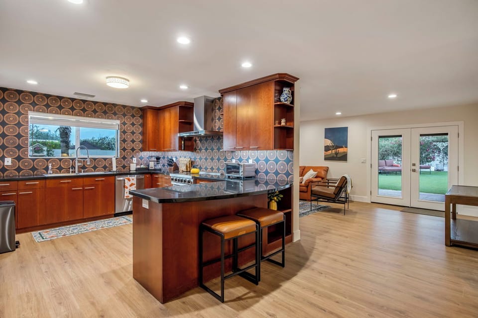A kitchen built to feed eight — stone peninsula, big range, cherry cabinets the length of the room.