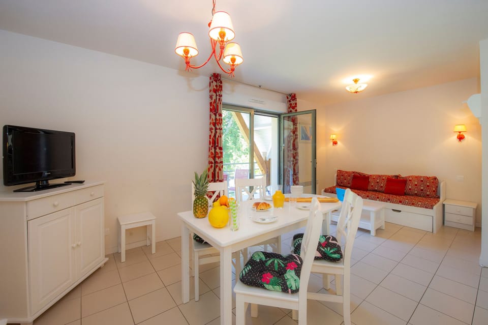 Another angle of the living space showing the sofa, dining set, and open balcony doors onto the terrace