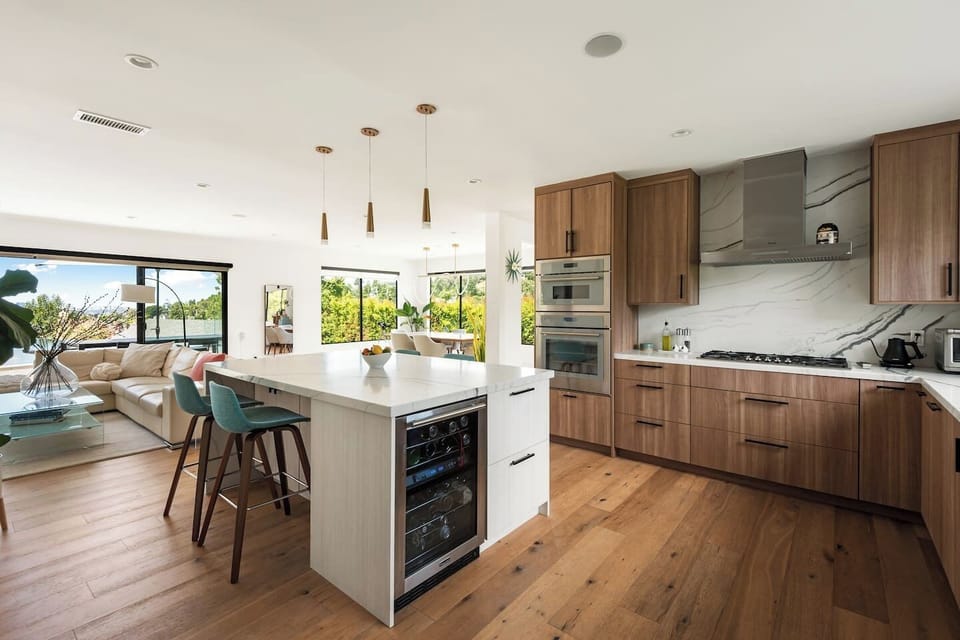A sleek and fully equipped kitchen with premium appliances, a built-in wine fridge, marble countertops, and an open layout that flows seamlessly into the living area — perfect for entertaining