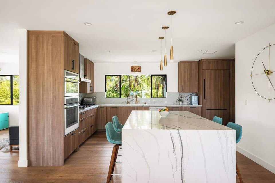 A beautifully designed chef`s kitchen featuring rich walnut cabinetry, marble countertops, modern appliances, and garden views — everything you need to cook, gather, and feel right at home.