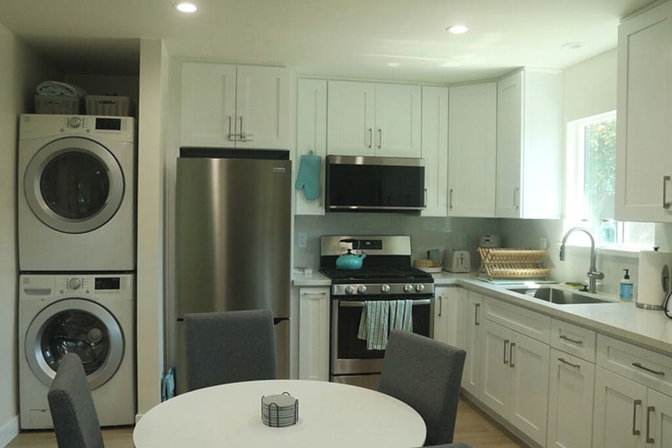 View of full kitchen, washer/dryer, dining area, afternoon light