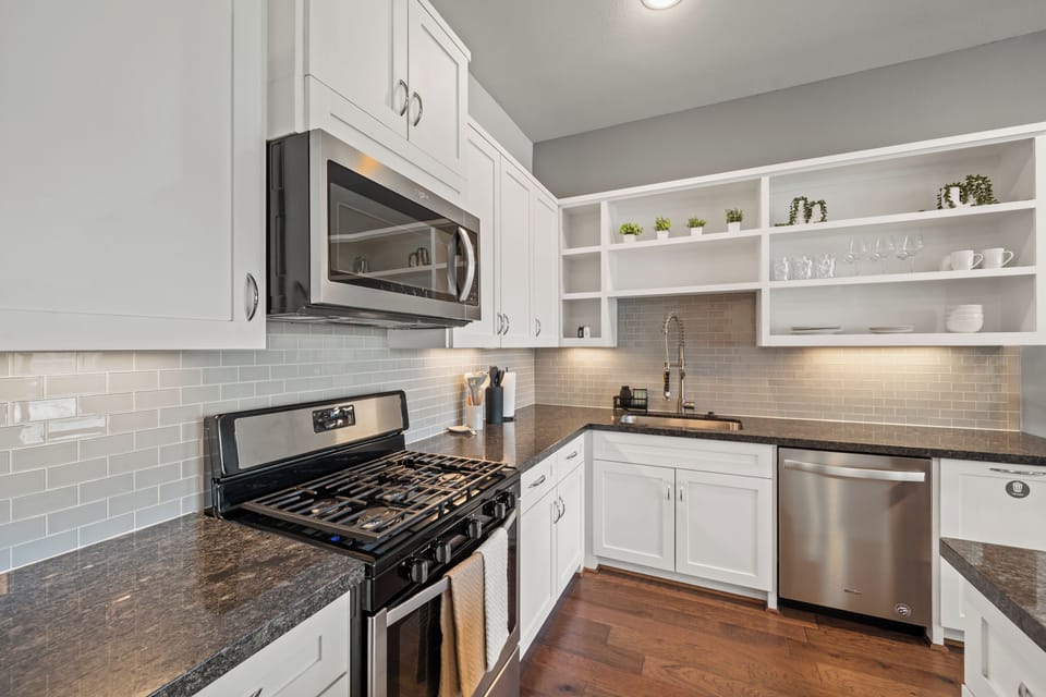 Bright modern kitchen with gas range, stainless appliances, and open shelving