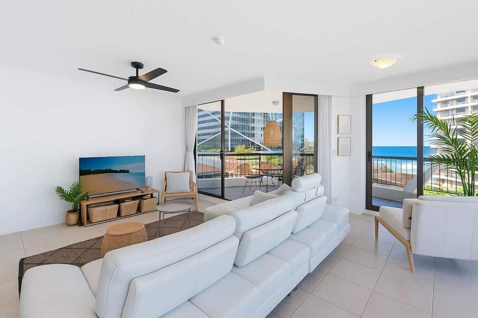 Second angle of the living room highlighting open space and balcony access, single sofa bed