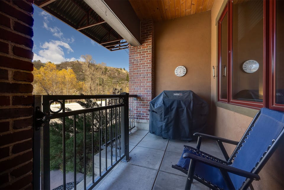 Unwind on your private balcony with stunning mountain views and autumn foliage, featuring comfortable seating and a Weber grill.