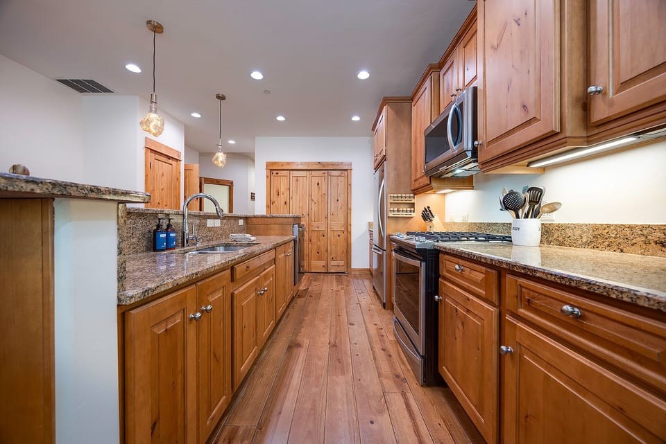 Cook your favorite meals in this spacious gourmet kitchen featuring granite countertops, stainless steel appliances, and warm wood cabinetry.