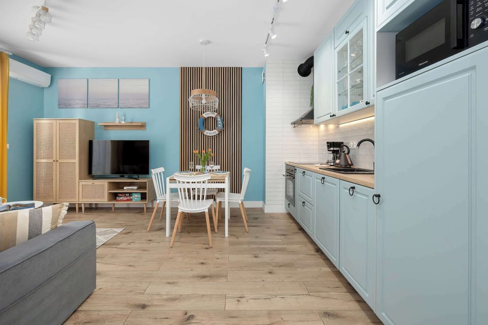 The kitchen cabinetry extends along the wall, featuring integrated appliances like a microwave and oven. The light blue color of the cupboards gives the space a fresh and modern look.