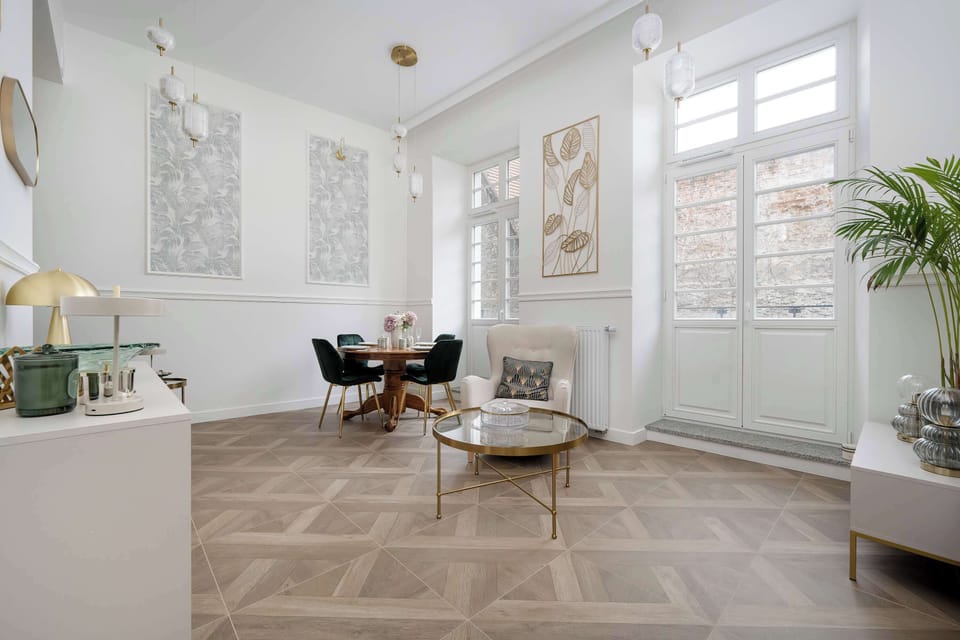The expansive living area is shown from the entrance, highlighting the flow between the seating and dining zones. The combination of Art Deco elements and modern furniture creates a high-end, curated look.