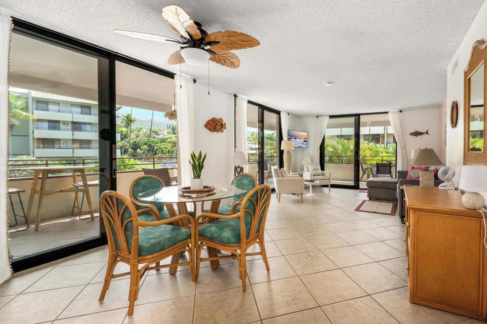 Relax in your tropical-themed open living space with ocean-inspired décor, surrounded by lush balcony views through floor-to-ceiling windows.
