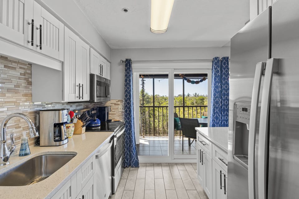 Your fully equipped kitchen opens to a private balcony with treetop views, perfect for morning coffee or evening meals outdoors.