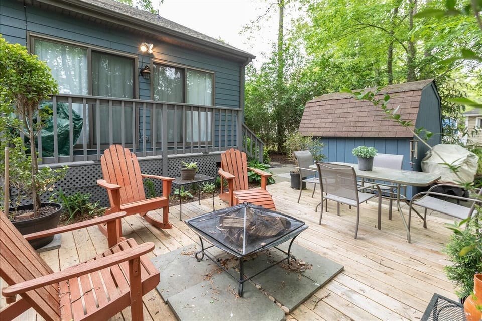 Private patio featuring red chairs, a firepit, and a gas BBQ set against a backdrop of greenery