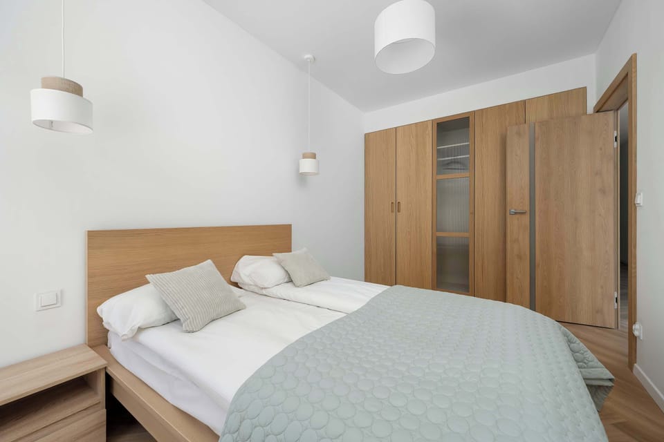 A comfortable bed with a padded headboard and neatly arranged pillows, creating a restful atmosphere. Soft lighting and minimal decor enhance the calm, uncluttered feel of the space.