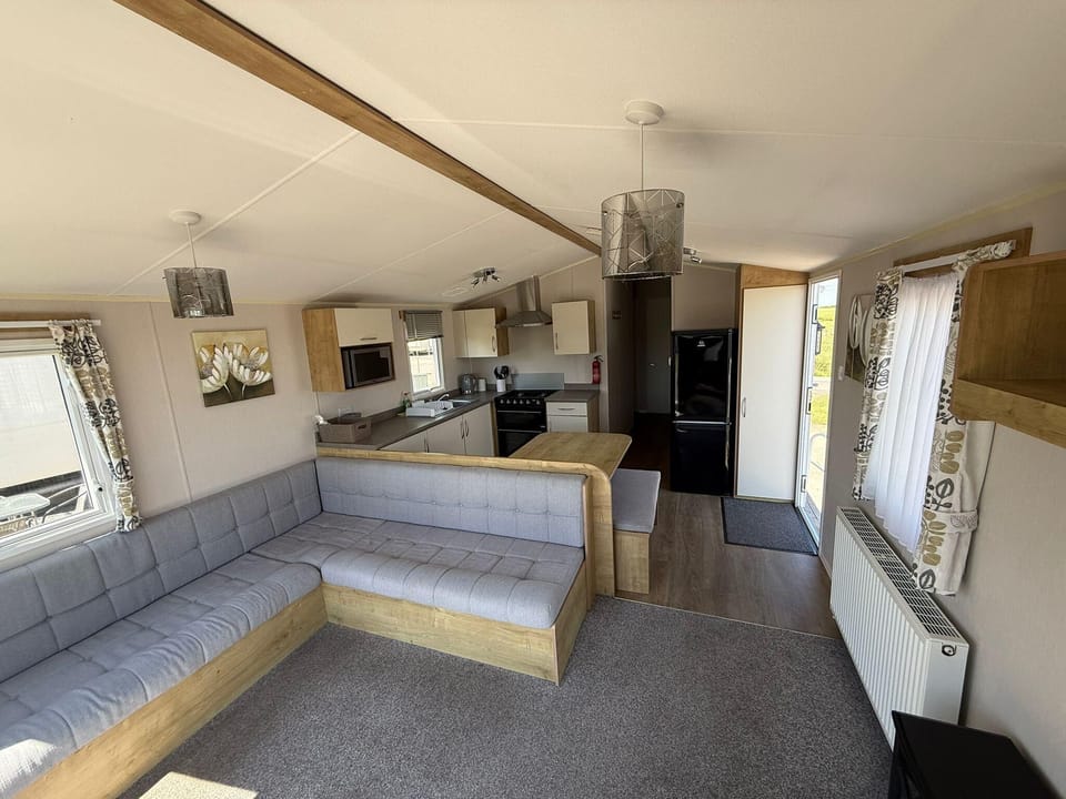 Modern family holiday UK caravan interior at Steeple Bay Holiday Park with open-plan lounge, dining area and kitchen.
