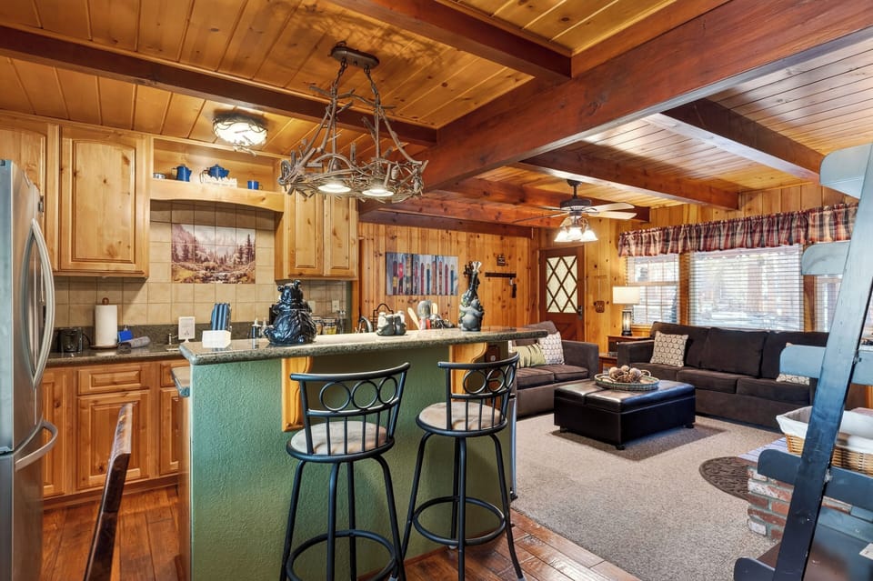 An open kitchen with bar seating flows into the cozy living area for easy gathering after a day in Big Bear.