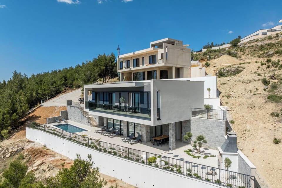 An aerial view of the villa shows its architecture and surrounding landscape.