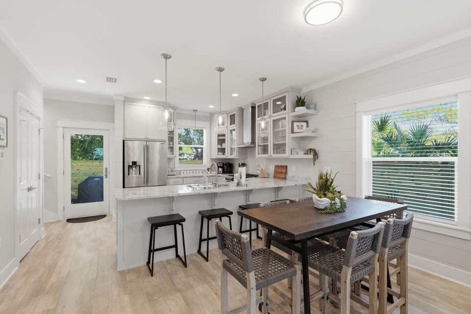 Cook and dine together in your bright, modern kitchen featuring white cabinets, marble countertops, and stylish island seating.