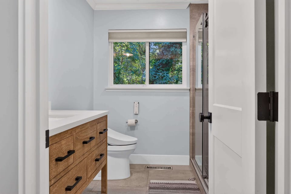 Glass-enclosed shower and tiled floors round out this spa-style bath, framed by treetops just outside the window.