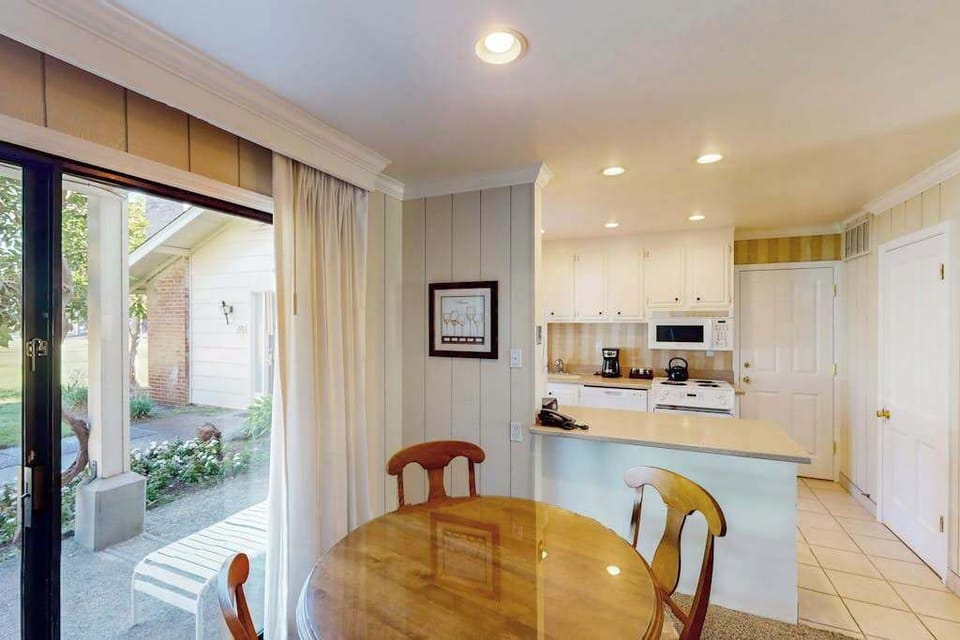 Brew your morning coffee and cook a leisurely breakfast in the fully equipped kitchen — white cabinetry and patio-door light keep the space airy and inviting.