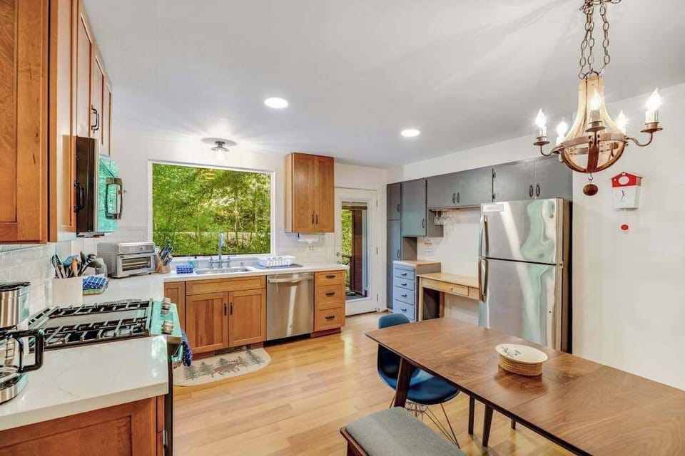 Everything you need to prepare a gourmet Cazadero dinner — gas range, stainless dishwasher, coffee maker, and leafy green views from the oversized window.