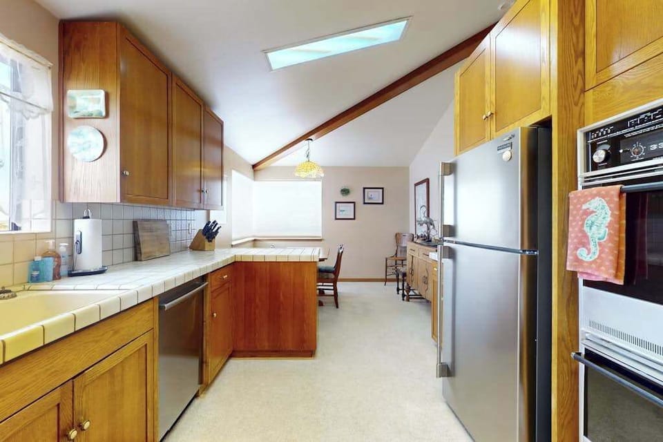 Your galley-style kitchen connects seamlessly to the dining nook, with a wall oven, refrigerator, and skylit coastal ambiance